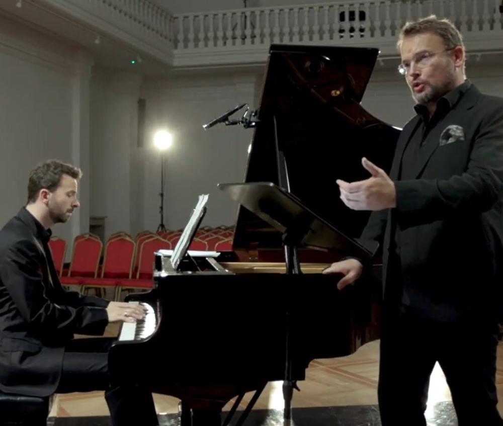 Bas-baryton Tomasz Konieczny śpiewa pieśni Moniuszki wspólnie z pianistą Lechem Napierałą, obaj artyści ubrani są w czarne stroje