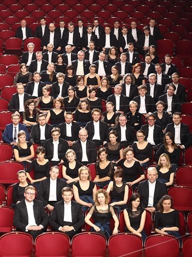 Na widowni w sali koncertwej siedzą muzycy Orkiestry Akademii Beethovenowskiej bez instrumentów w strojach koncertowych - panowie we frakach, panie - w sukniach